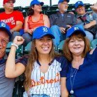 Two parents and their daughter sit in their seats cheering for the tigers